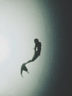 the silhouette of a person jumping in the air with a surfboard under their arm