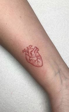 a small red heart tattoo on the arm