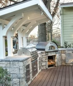 an outdoor bbq and grill area with wood flooring in front of a house