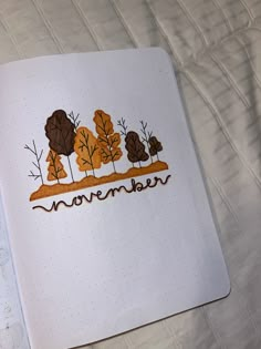 an open notebook with the word november written in brown and orange trees on top of it