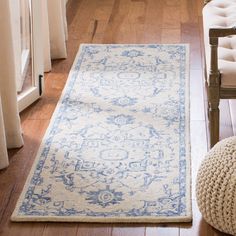 a white and blue rug on the floor next to a chair in a living room