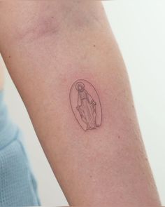 a woman's arm with a small tattoo of a person holding a baby jesus