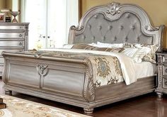 a silver bed sitting on top of a wooden floor next to a dresser and mirror