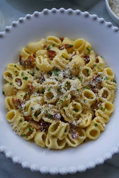 a white bowl filled with pasta covered in parmesan cheese