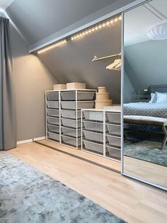 an attic bedroom with mirrored closet doors and storage bins on the floor next to a bed