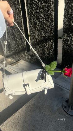 someone is holding a fake flower and pulling it out of a purse on the sidewalk