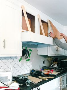 a man is working on the cabinets in his kitchen