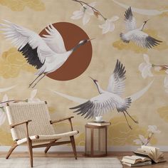 two birds flying in the sky over a wall with flowers on it and a chair