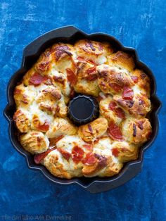 a pizza with cheese and pepperoni in a pan on a blue tableclothed surface