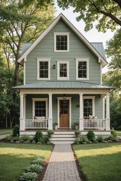 a green house with white trim on the front porch and two story entryway to the second floor