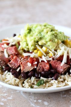 a white plate topped with rice, beans and guacamole on top of it