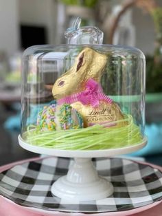 an easter cake under a glass dome on top of a table