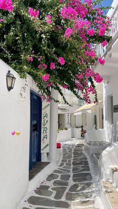 an alley way with pink flowers growing over the doorways and steps leading up to it