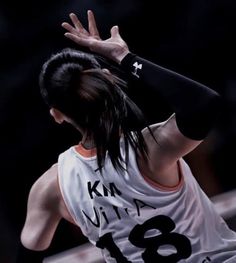 a woman holding her hands up in the air while wearing a white shirt with black writing on it