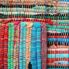 multicolored rugs are stacked on top of each other in an area that looks like it could be used as a wall hanging decoration