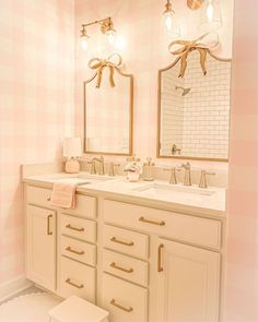 a bathroom with two sinks, mirrors and lights on the wall above them is decorated in pink and white checkered walls