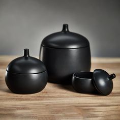 three black pots and two cups on a wooden table