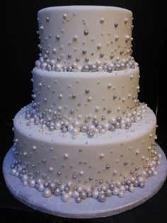 a three tiered white wedding cake with pearls