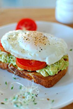 an egg and tomato sandwich is on a white plate