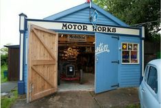 a blue garage with an open door that says motor works on the front and side