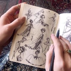 a person holding a pen and looking at an open book with drawings on the pages