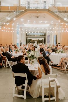 a bride and groom sitting at their wedding reception