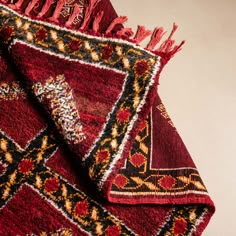 a red and black area rug with tassels on the edges, laying flat