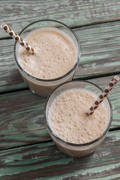 two glasses filled with milk sitting on top of a wooden table