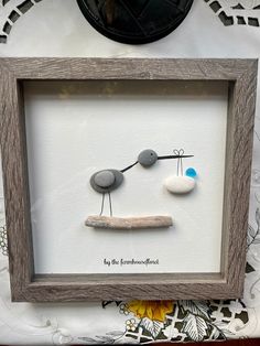 a wooden frame holding two rocks and a small piece of artwork on top of a table