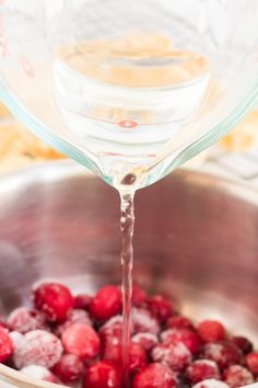 water pouring into a pot filled with raspberries