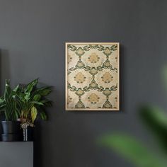 a wall hanging on the side of a gray wall next to a potted plant