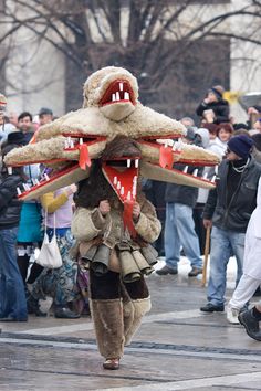 a man in costume walking down the street while holding onto a large stuffed animal's head