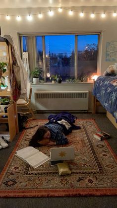 a person laying on the floor in front of a bed with lights strung over it