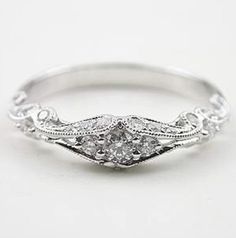 a white gold ring with an old - fashioned design and diamonds on the band,