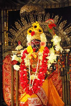 an idol with flowers and garlands on it's head in front of a stage