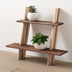 a wooden shelf with two planters on top and the words west elm above it