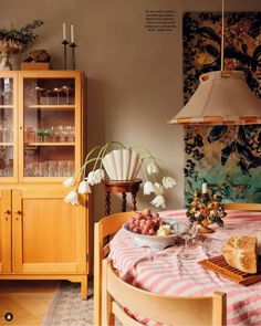 a dining room table with food on it and wine glasses in front of the china cabinet