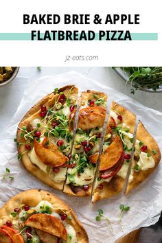 two small pizzas with toppings sitting on top of white paper next to bowls and utensils