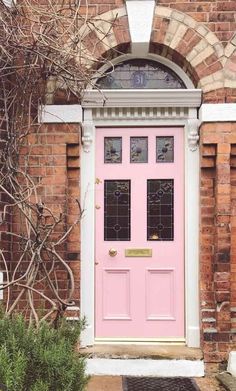 two blue and pink doors in front of a red brick building with potted plants