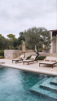 two lounge chairs sitting next to a swimming pool