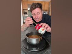 a man is stirring something in a pot on the stove top while holding a spoon