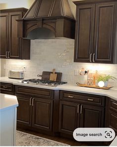 a kitchen with dark wood cabinets and white counter tops, along with an oven hood