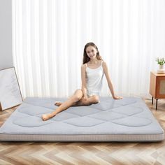 a woman sitting on top of a mattress in a room