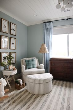 a baby's room with blue walls and striped rugs on the floor, white rocking chair