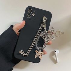 a person holding an iphone case with charms attached to it