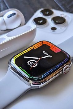 an apple watch sitting on top of a white table next to two other watches and accessories