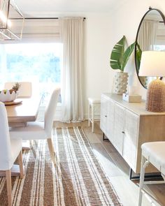 a dining room table with white chairs and a large mirror on the wall above it