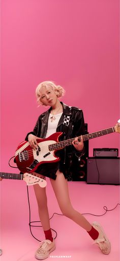 a woman with blonde hair is holding a guitar and posing in front of a pink background