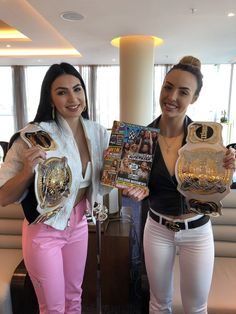 two women are holding up their wrestling belts