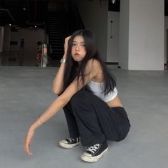 a woman sitting on the floor with her hand in her hair and wearing black pants